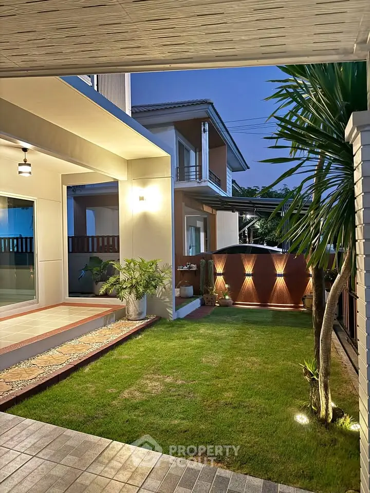 Charming modern home with a beautifully landscaped garden and elegant lighting, perfect for evening relaxation.