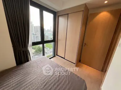 Modern bedroom with large window and built-in wardrobe offering city views