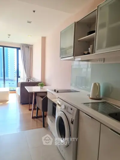 Modern apartment with open kitchen and living area, featuring a washing machine and city view.