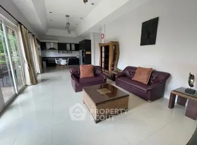 Spacious living room with modern furniture and open kitchen layout, perfect for entertaining.
