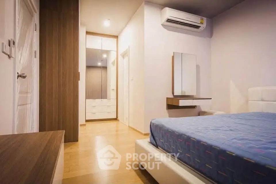 Modern bedroom with wooden flooring and air conditioning in a stylish apartment.