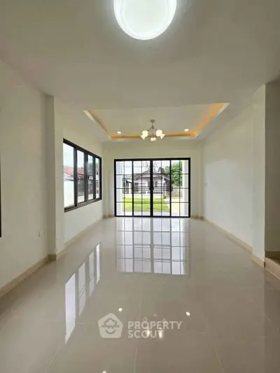 Spacious living room with large windows and modern lighting in a bright home.