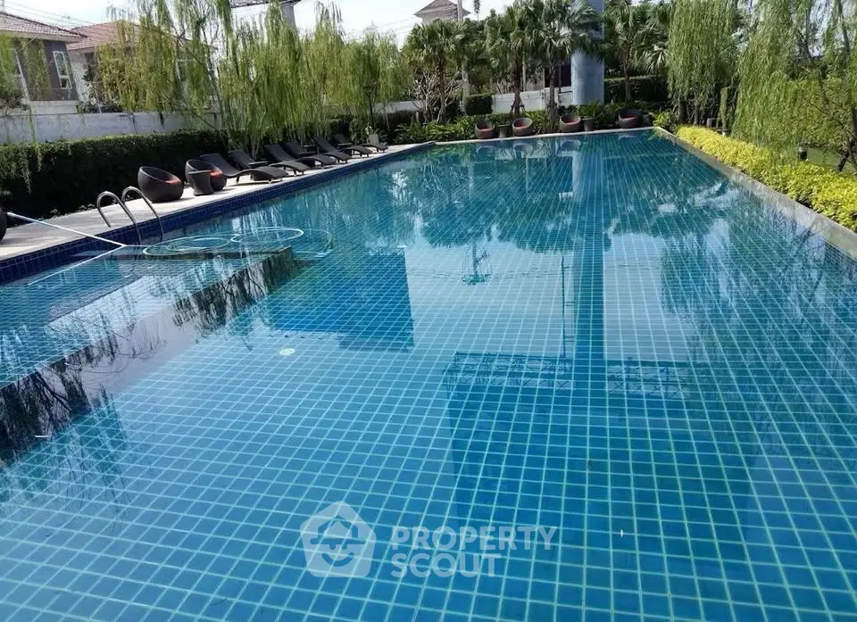Luxurious outdoor swimming pool with lush greenery and modern lounge chairs, perfect for relaxation and leisure.