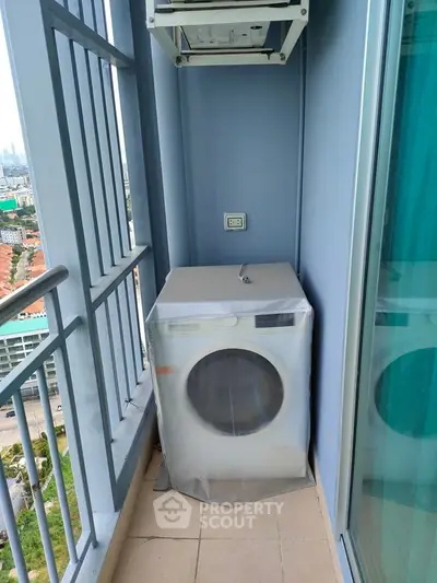 Compact balcony with washing machine and city view, ideal for urban living convenience.