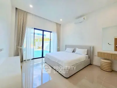 Luxurious bedroom with pool view, modern decor, and ample natural light in a high-end property.