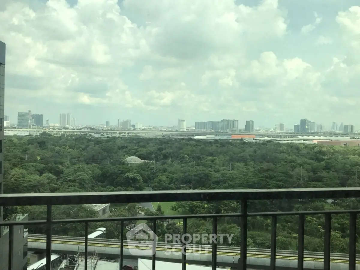 Stunning cityscape view from a high-rise balcony overlooking lush greenery and urban skyline.