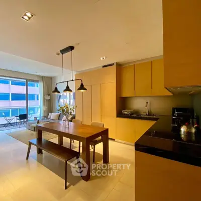 Modern open-layout kitchen and dining area with wooden cabinetry and stylish lighting.