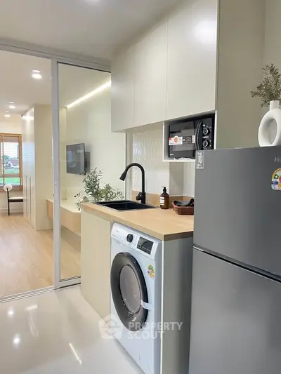 Modern kitchen with sleek appliances and washing machine in stylish apartment.