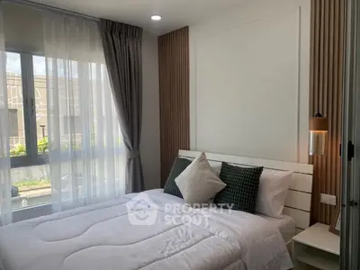 Cozy modern bedroom with stylish decor and large window for natural light.