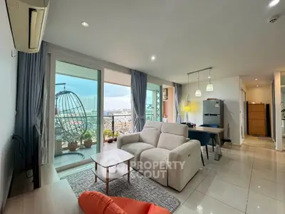 Spacious modern living room with balcony and city view, featuring cozy seating and stylish decor.