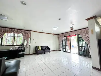 Spacious living room with large windows and elegant curtains, perfect for family gatherings.