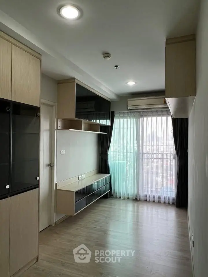 Modern living room with large windows and built-in storage, featuring sleek wooden flooring.
