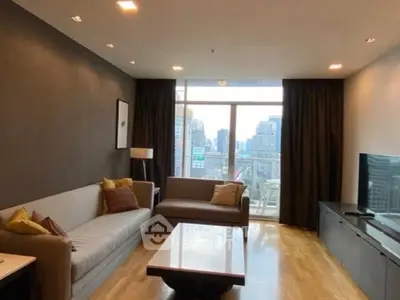 Modern living room with city view, featuring sleek furniture and large windows.