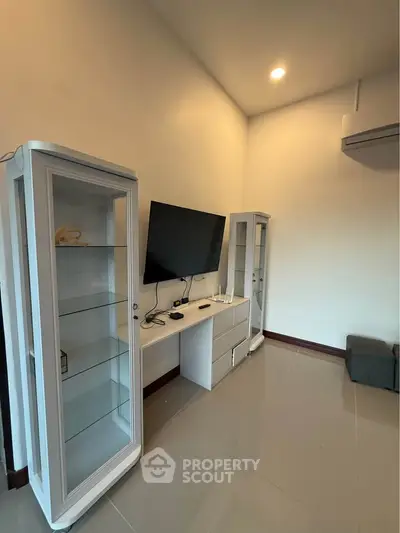 Modern living room with sleek TV setup and glass display cabinets