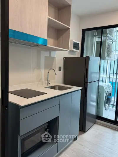 Modern compact kitchen with sleek appliances and balcony view