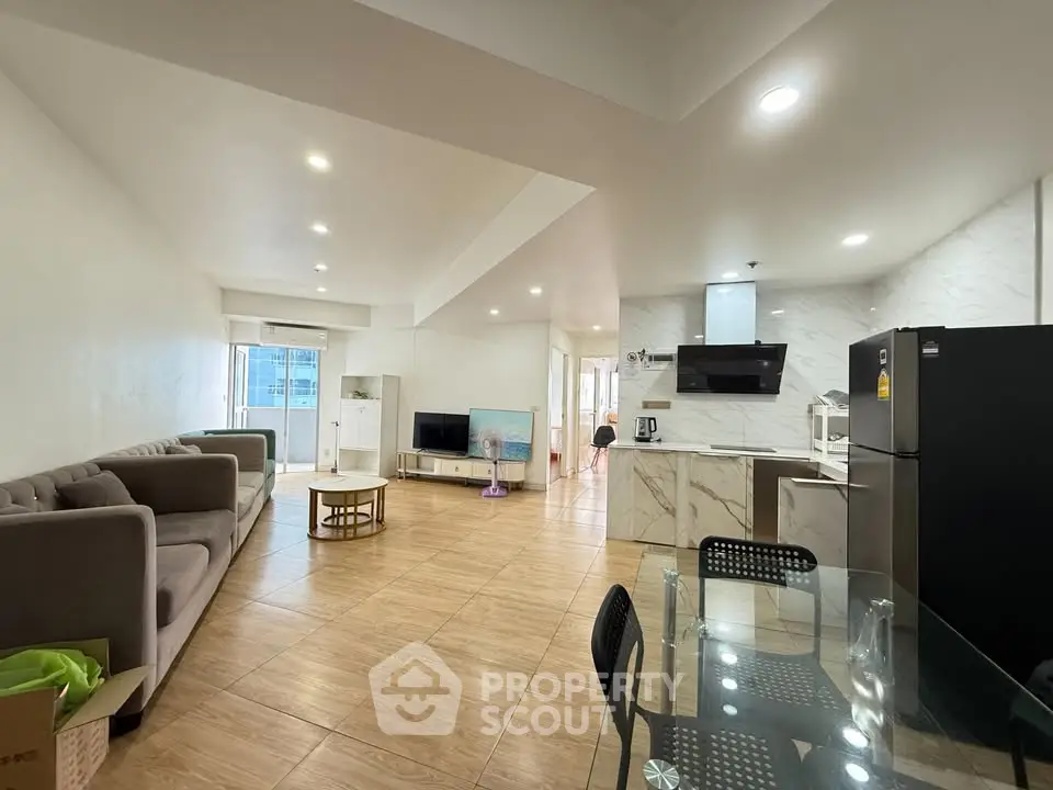 Spacious open-plan living room and kitchen with modern furnishings and natural light.