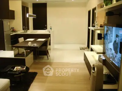Modern open-layout living room with kitchen, featuring sleek furniture and ambient lighting.