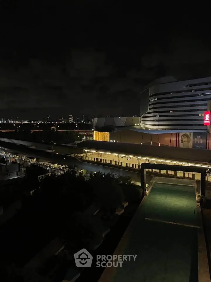 Stunning night view of modern building with illuminated pool and city skyline.