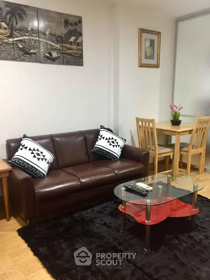 Cozy living room with leather sofa, glass coffee table, and dining area in modern apartment.