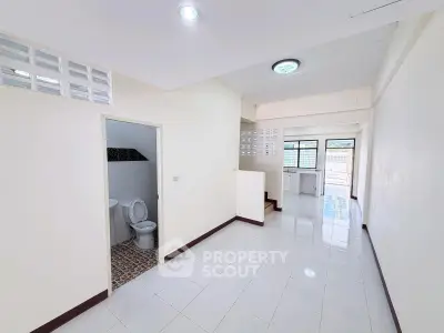 Spacious open-plan living area with tiled floors and natural light, featuring a modern kitchen and bathroom.