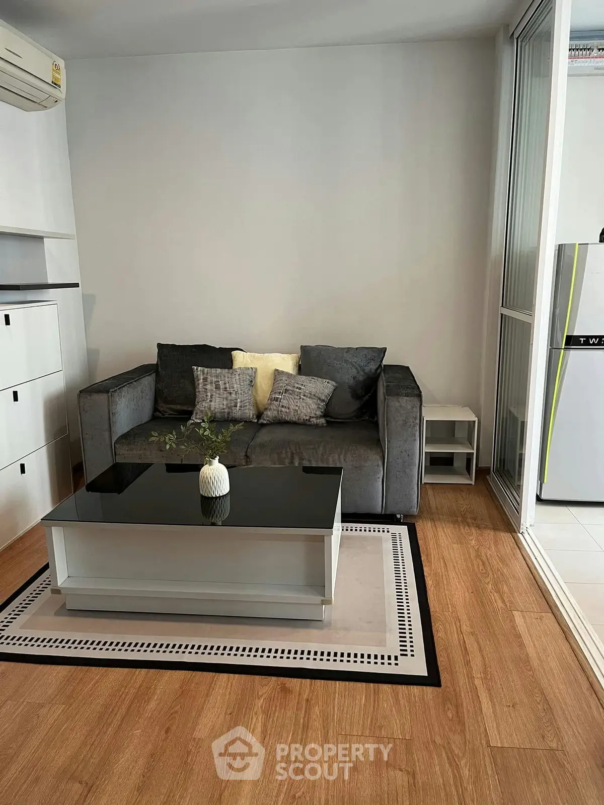 Modern living room with sleek sofa and glass coffee table on wooden floor