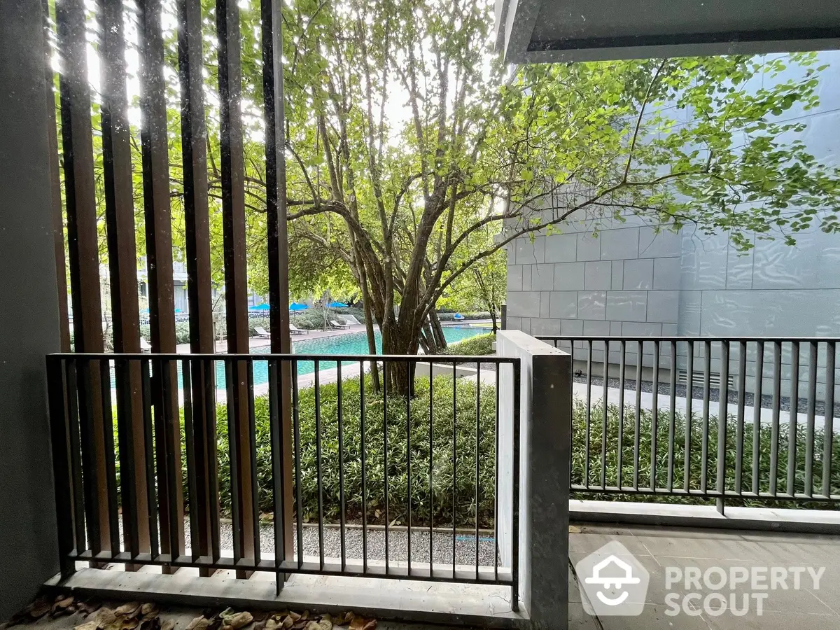 Serene balcony view overlooking a lush garden and tranquil pool, perfect for relaxing outdoor living in a modern urban residence.