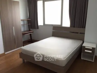 Modern bedroom with wooden furniture and large window for natural light.