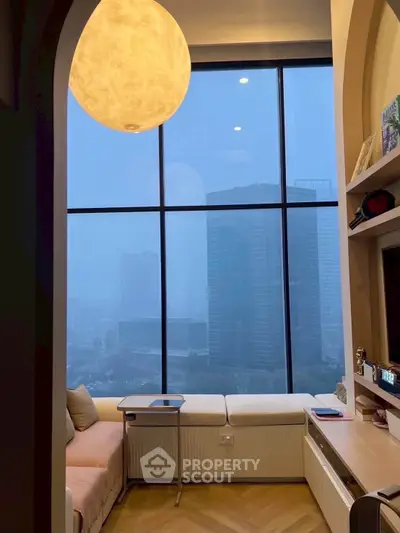 Modern living room with large windows offering stunning city views, cozy seating, and elegant lighting.