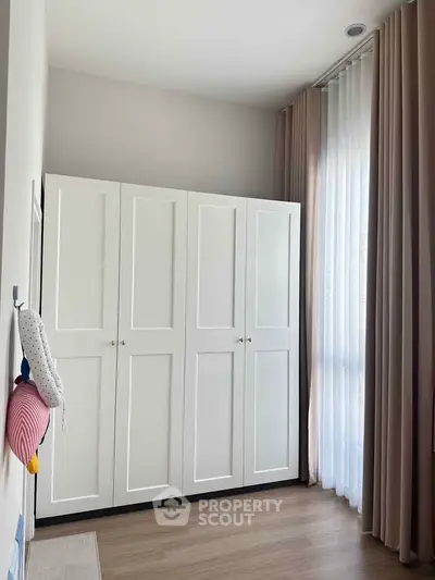 Bright bedroom with white wardrobe and floor-to-ceiling curtains