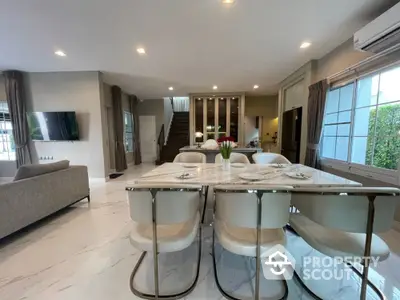 Spacious modern living area with elegant dining set, sleek marble floors, and a cozy lounge space leading to an inviting staircase.