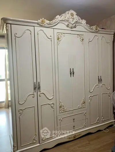 Elegant vintage wardrobe with ornate detailing in a spacious bedroom setting.