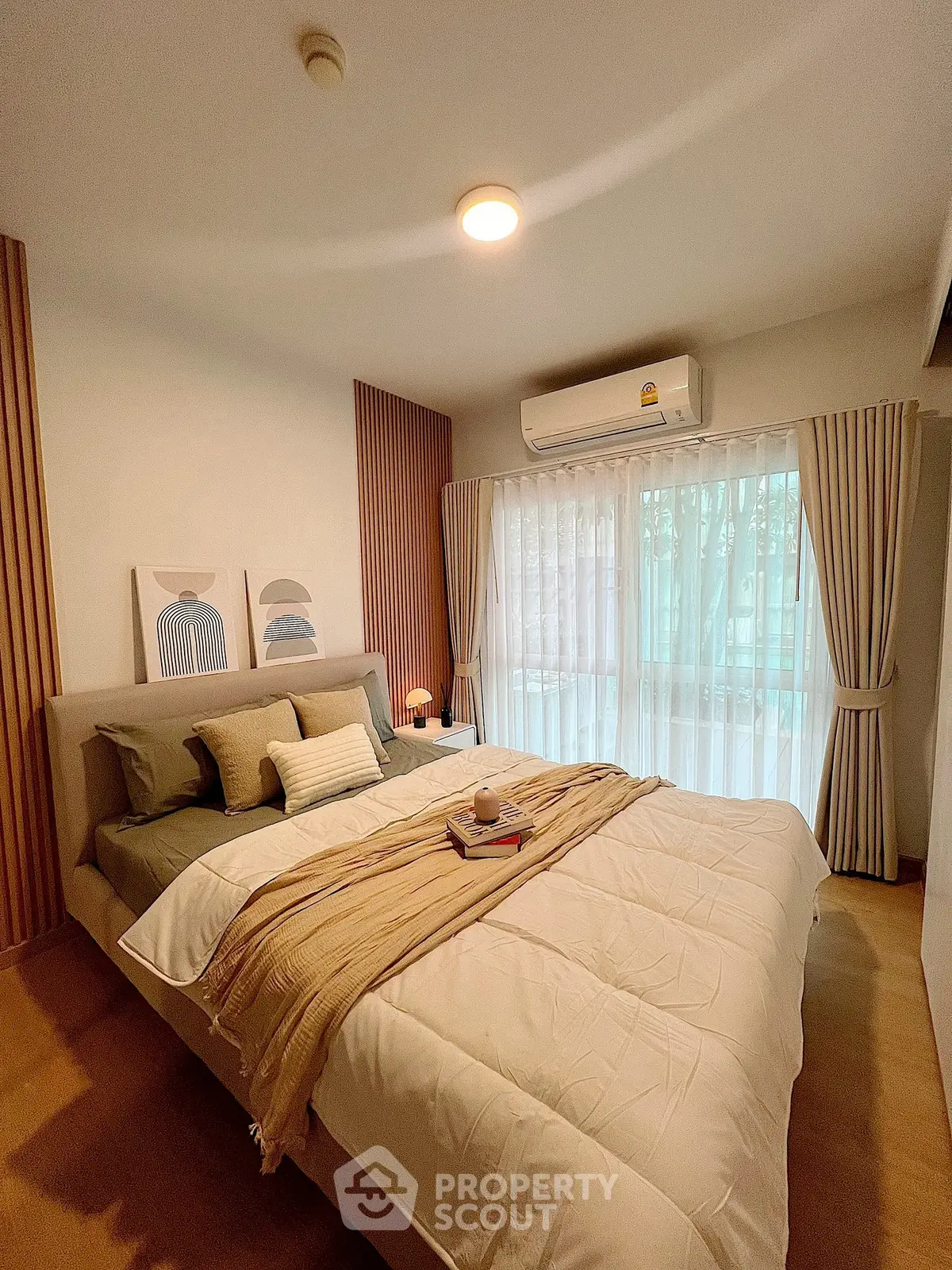 Cozy bedroom with stylish decor and natural light through large windows.