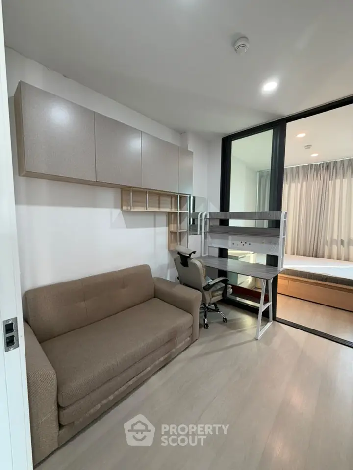 Modern studio apartment with cozy living area and bedroom, featuring sleek furniture and ample natural light.