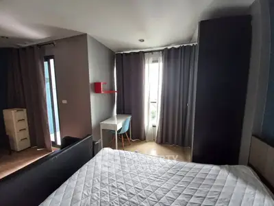 Modern bedroom with large window and stylish furnishings in a contemporary apartment.