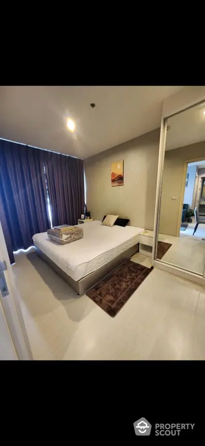 Modern bedroom with stylish decor and large mirror wardrobe