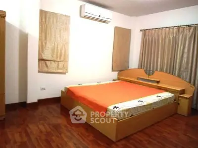 Spacious bedroom with wooden flooring and modern furnishings