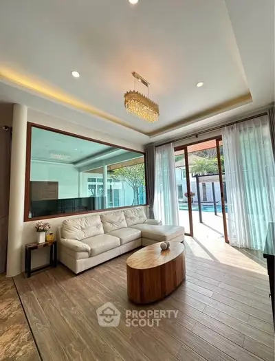 Luxurious living room with pool view, elegant chandelier, and modern furnishings in a spacious open layout.