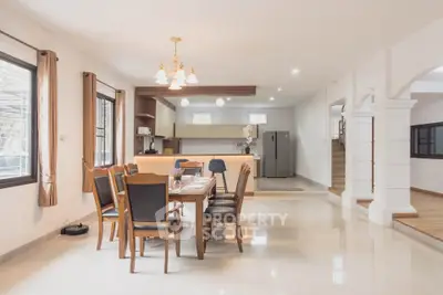 Spacious open-plan dining area with elegant wooden furniture and modern kitchen.