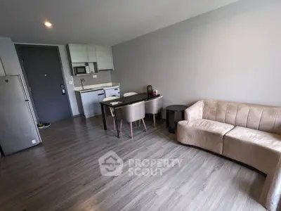 Modern living room with open kitchen, sleek flooring, and cozy seating area in a stylish apartment.
