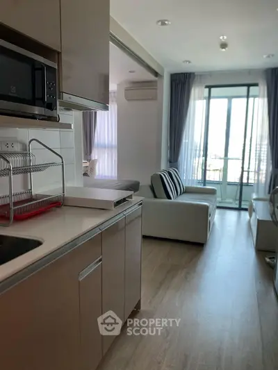 Modern open-layout kitchen and living room with balcony view in a stylish apartment.