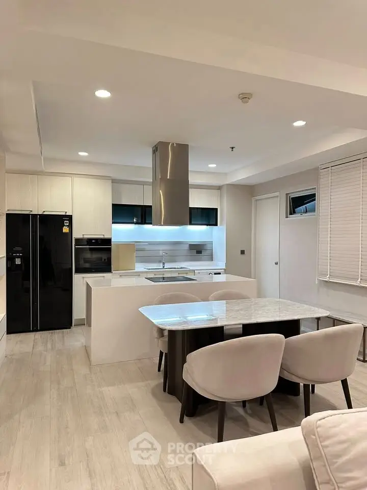 Modern kitchen with sleek design, featuring an open layout, marble dining table, and high-end appliances.
