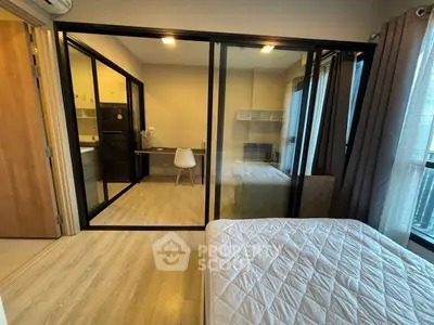 Modern bedroom with glass partition, cozy study area, and natural light.