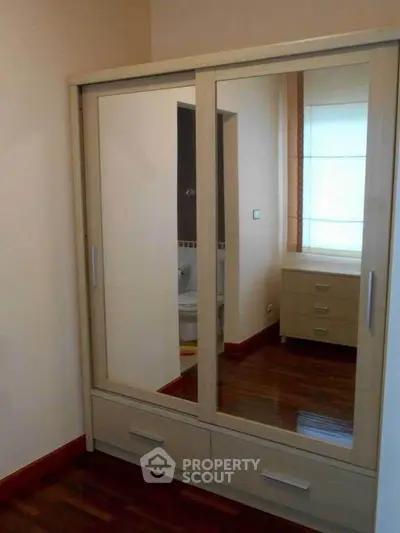 Spacious bedroom with mirrored wardrobe and wooden flooring