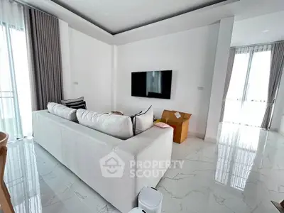 Modern living room with sleek white sofa and wall-mounted TV, featuring elegant marble flooring.