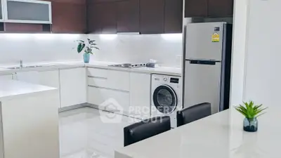 Modern kitchen with sleek white cabinets, integrated appliances, and stylish dining area.