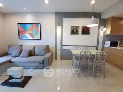 Modern living room with stylish decor and open kitchen layout, featuring a cozy sofa and dining area.