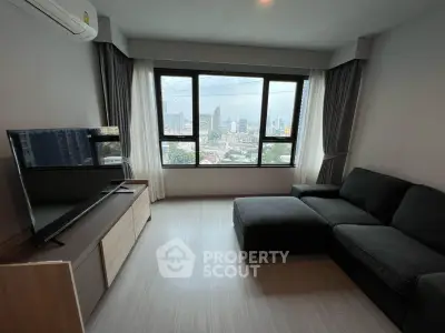 Modern living room with city view, featuring sleek furniture and large windows for natural light.