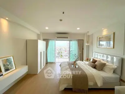 Spacious modern bedroom with balcony and city view, featuring elegant decor and natural light.