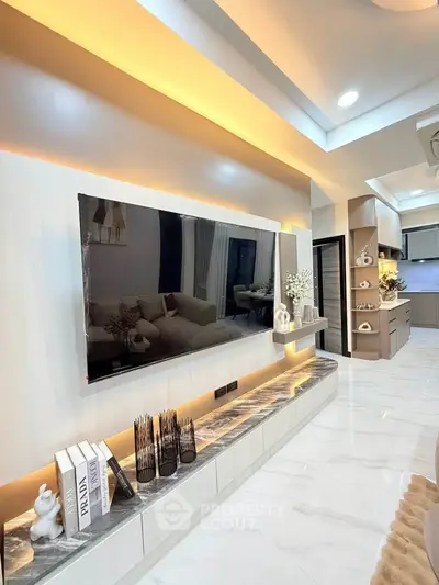 Modern living room with sleek TV setup and elegant decor, featuring open layout to contemporary kitchen.