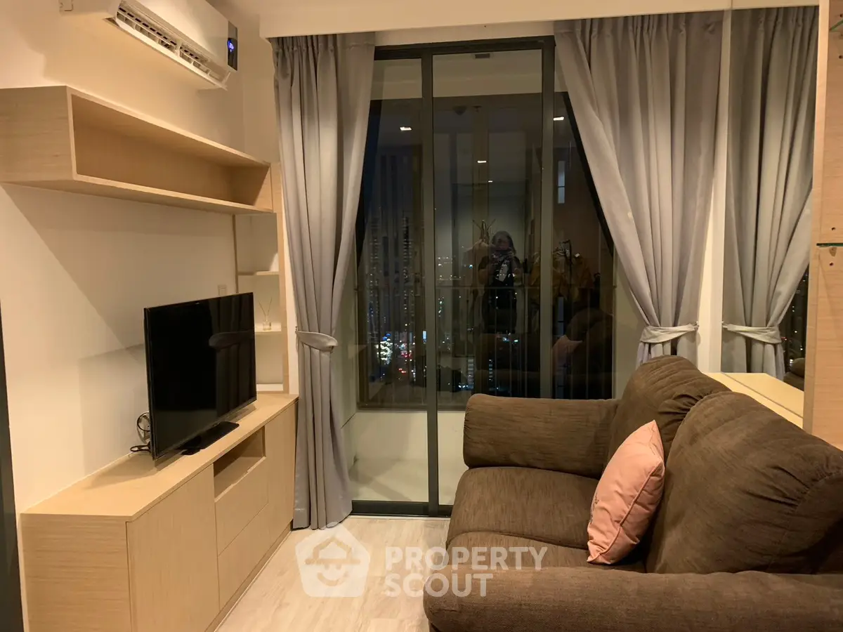 Cozy living room with modern decor and balcony view in urban apartment.